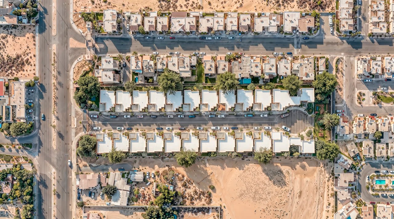 Vista aérea diurna del residencial y su entorno: la traza de la colonia, las vialidades de acceso y el desierto abierto al sur.